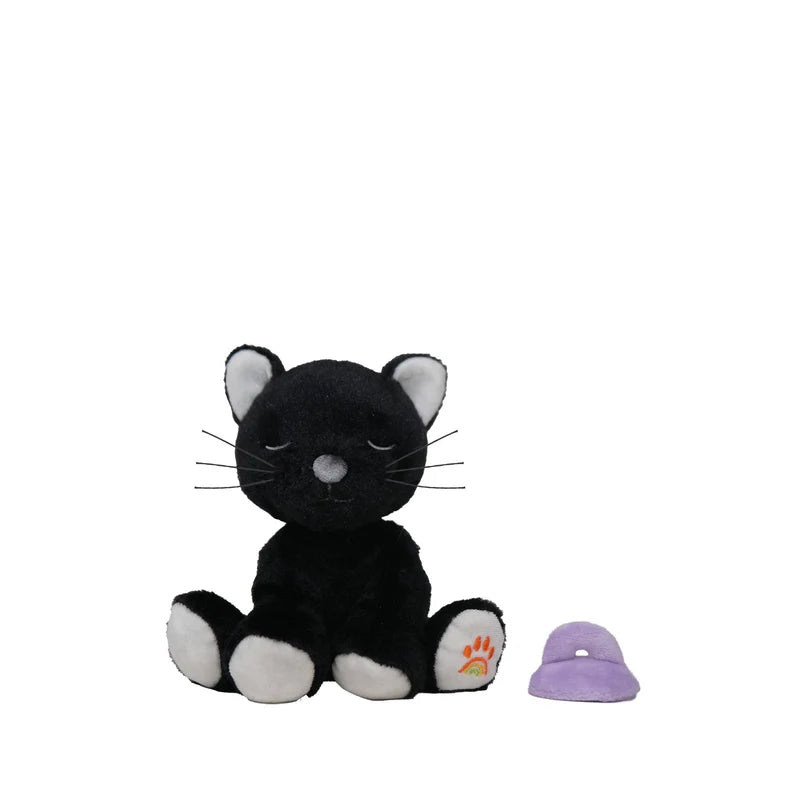The Olli Ella Binky Kitten Koko - Black, a plush cat with closed eyes, white paws, and inner ears, sits beside a small purple toy hat on a white background—perfect for Playtopia Koko fans.