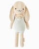 Cuddle + Kind Briar the Bunny - Light Blue is a beige, hand-knit doll made from premium cotton yarn, featuring long ears, embroidered eyes and smile, pink cheeks, and a light blue romper with a cute bunny face—handmade in Peru.