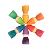 A circular arrangement of colorful wooden Grapat Rainbow Tomtens on a white background, featuring various colors including green, blue, orange, and purple.