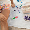 A child plays with Grapat Mix & Match cubes on a white blanket outdoors, carefully arranging them by color. The focus is on the child's hands and the vibrant cubes.