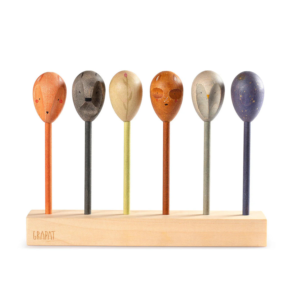 The Grapat Twin Souls Puppets feature six colorful wooden spoon figures with painted animal faces in a wooden base, perfect for storytelling. Each vibrant spoon has a unique expression, creating an artistic arrangement reminiscent of double-faced puppets, ideal as delightful children's toys.