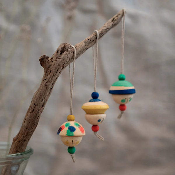 Three small, hand-painted figures from the Grapat Ornament Set - No 8 - Kind Folks hang by strings, each with colorful patterns and beads, perfect for festive decor on a branch or tree.