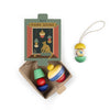 A set of colorful, hand-painted wooden ornaments from Grapat Ornament Set - No 9 - Pure Shine sits next to a box featuring a cat and lights; one ornament hangs from a string, others rest in an open cardboard tray.
