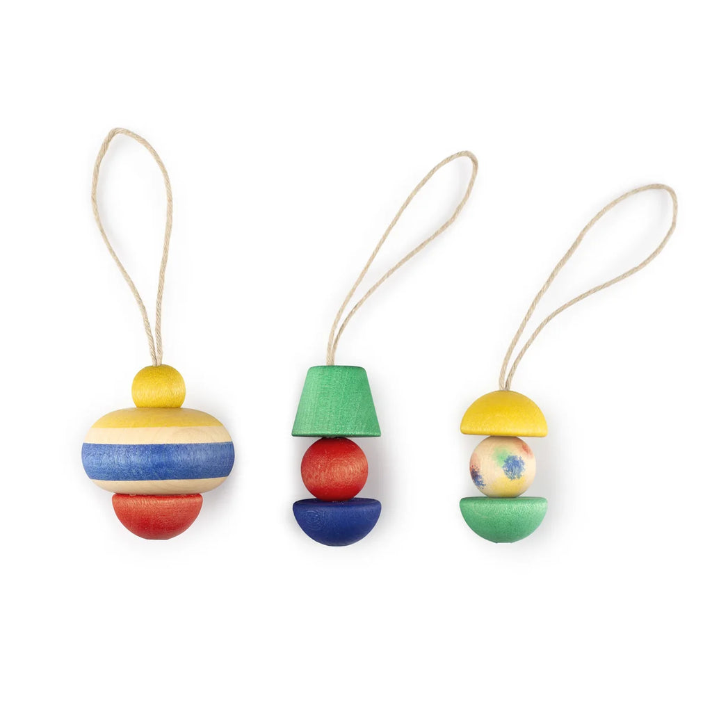 Three hand-painted wooden ornaments from the Grapat Ornament Set - No 9 - Pure Shine, each with unique shapes and geometric patterns in red, blue, green, and yellow, arranged side by side with string loops on a white background.