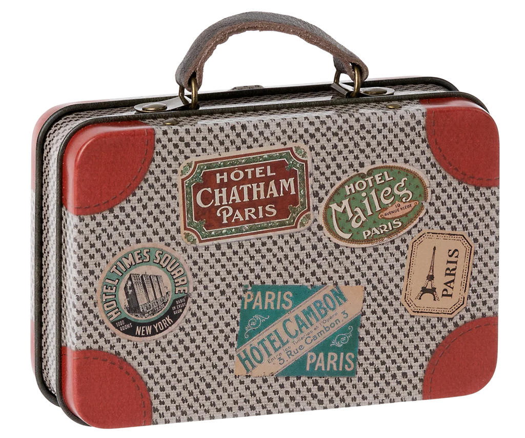 The Maileg Suitcase, Small is a charming vintage-inspired piece adorned with travel stickers from Paris and New York, red leather corners, and a textured pattern. Perfect for storing gifts or carrying small soft toys, this suitcase captures the whimsical style of Maileg’s iconic metal suitcases—an enchanting addition to any collection.