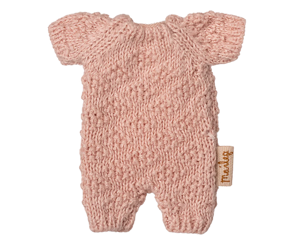 The Maileg Extra Clothing: Knitted Suit, Micro - Rose for Micro Bunny is a small pink knitted romper with short sleeves and legs, shown flat on a white background. A small tan fabric tag accents the side.