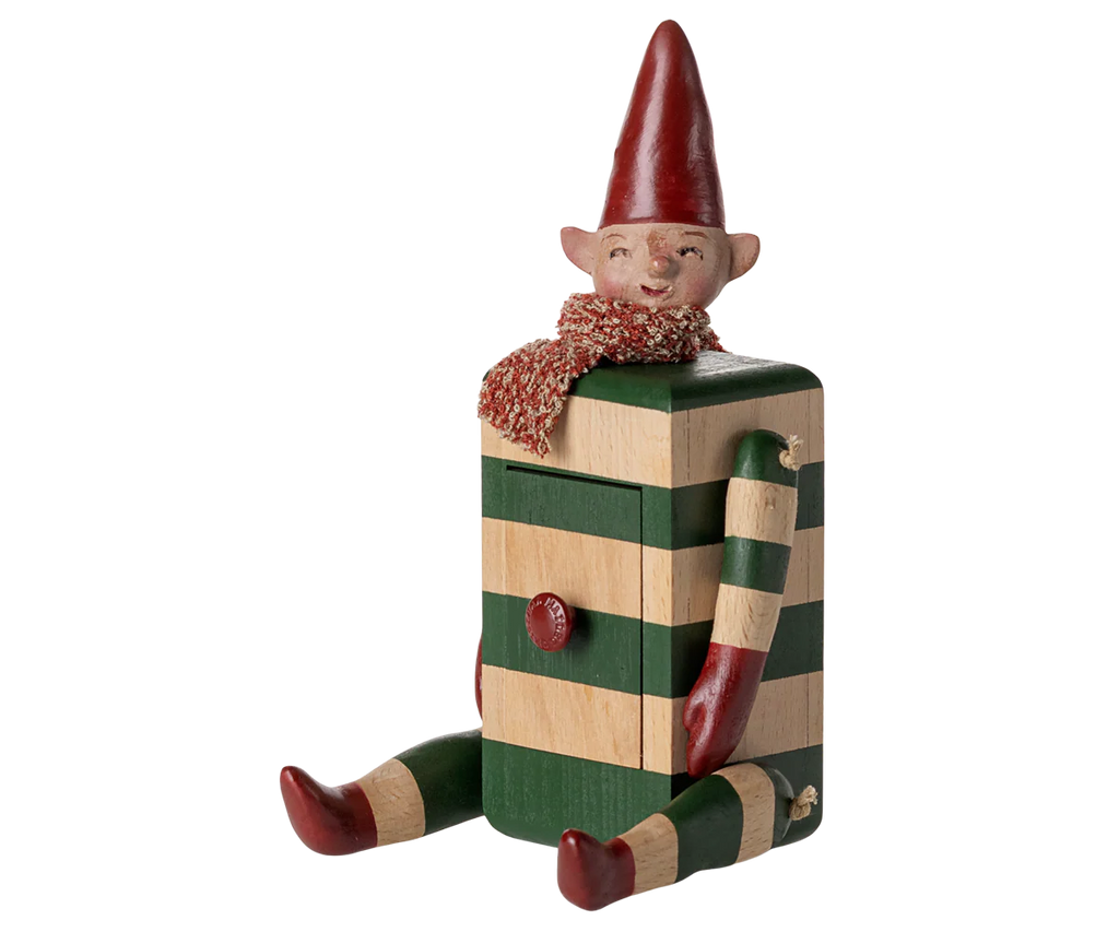 PRE-ORDER: Maileg Elf with Drawer - Green features a collectible wooden elf figurine with a striped green and beige body, red mittens, boots, scarf, and hat, pointed ears, a smiling face, and seated pose. Estimated arrival: mid August.