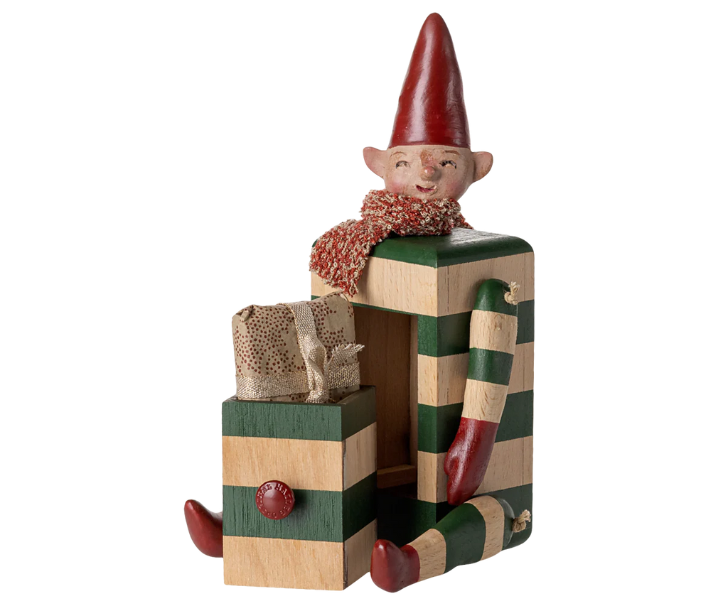 PRE-ORDER the Maileg Elf with Drawer - Green (estimated arrival mid August), a collectible elf with a red hat and scarf sitting on green and beige striped blocks, featuring striped arms and legs, plus a small gift box in front.