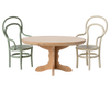The PRE-ORDER: Oval Dining Table, Mouse - Nature (ships early October) features quality craftsmanship and pairs beautifully with two bentwood chairs in green and cream, both with curved backs and cane seats—ideal for cosy dinner parties.