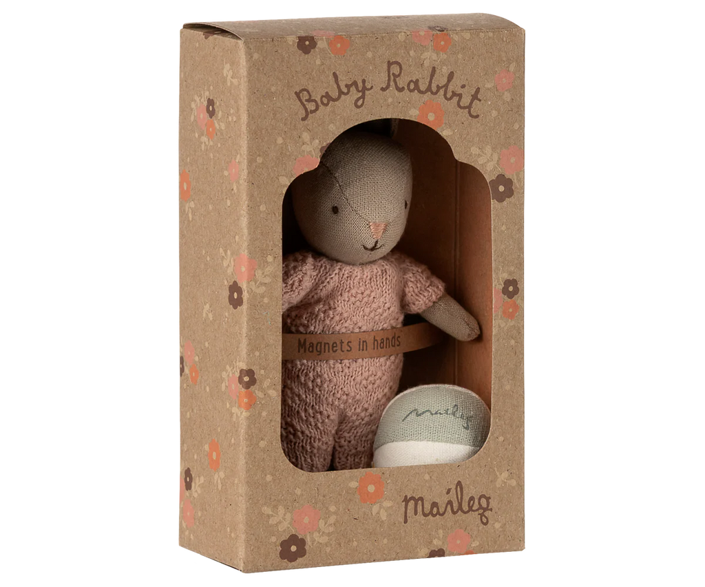 The Maileg Rabbit With Accessories, Micro - Sand - Rose is a boxed gift set featuring a soft rabbit in pink clothes with "Magnets in hands" on the box, a small fabric ball, floral brown packaging, and "Baby Rabbit" and "Maileg" labels.