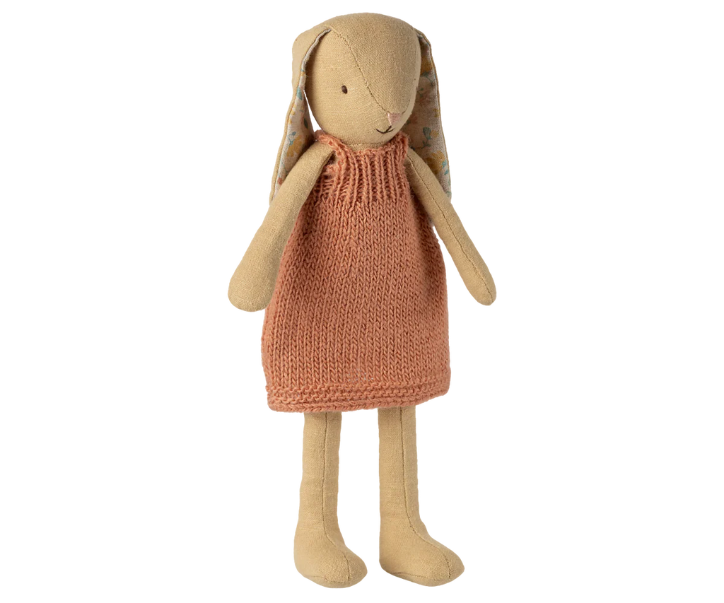 The Maileg Bunny, Size 2 in Cream Yellow, wears a sleeveless orange knitted dress and has long ears lined with a floral pattern. This soft linen doll stands upright against a plain white background.