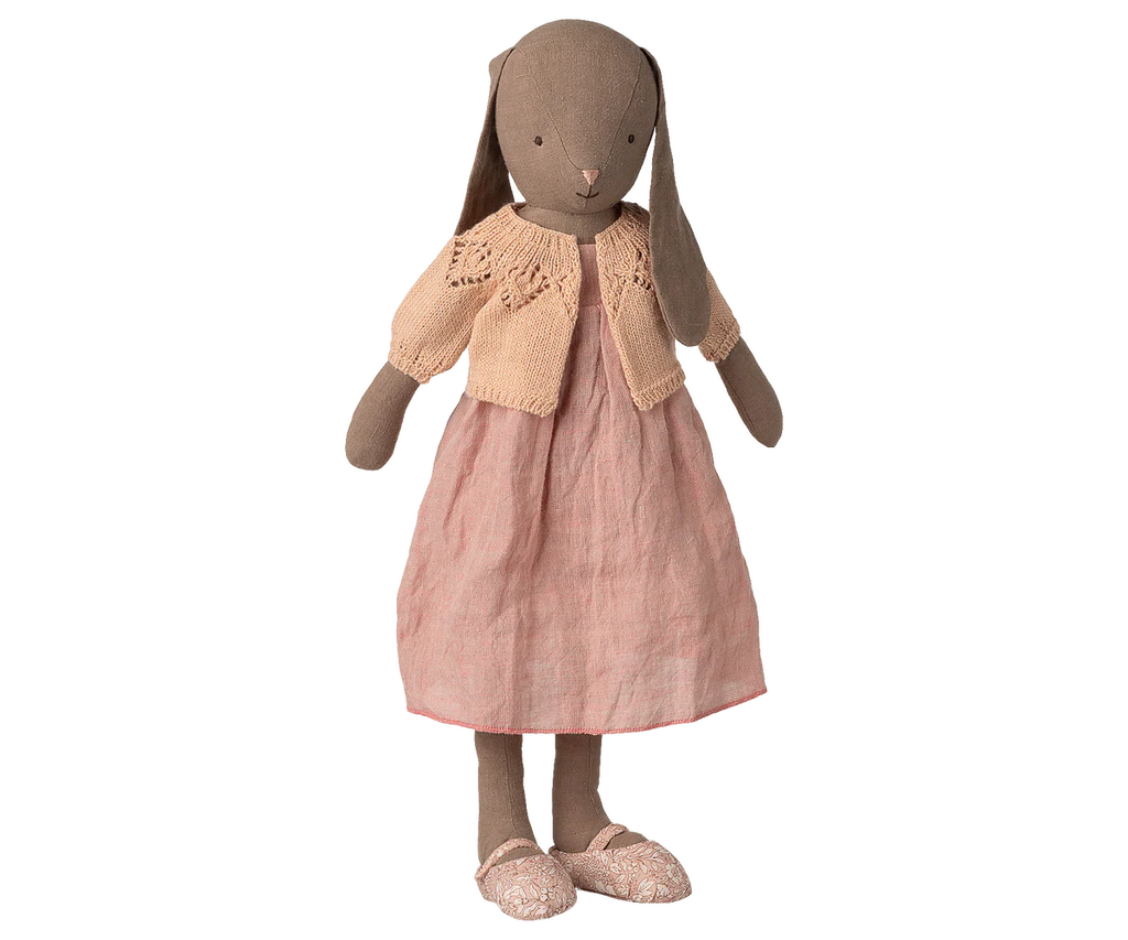 A brown fabric bunny doll stands upright against a white background, dressed in a pink dress with matching shoes and wearing the Maileg Knitted Cardigan, Size 4 - Light Rose (expected 02/15/26).