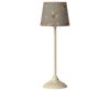 The Maileg Floor Lamp, Miniature - Sand, features a cream color and a slim base with a gray shade adorned with orange, white, and brown florals—ideal for adding charm to any dollhouse. Expected arrival: 03/15/26.