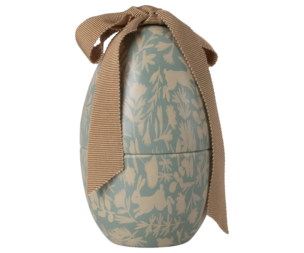 The Maileg Easter Egg, Small - Dusty Blue, is a pastel blue decorative metal egg featuring cream leaf, flower, rabbit, and bird illustrations, finished with a wide textured brown ribbon bow.