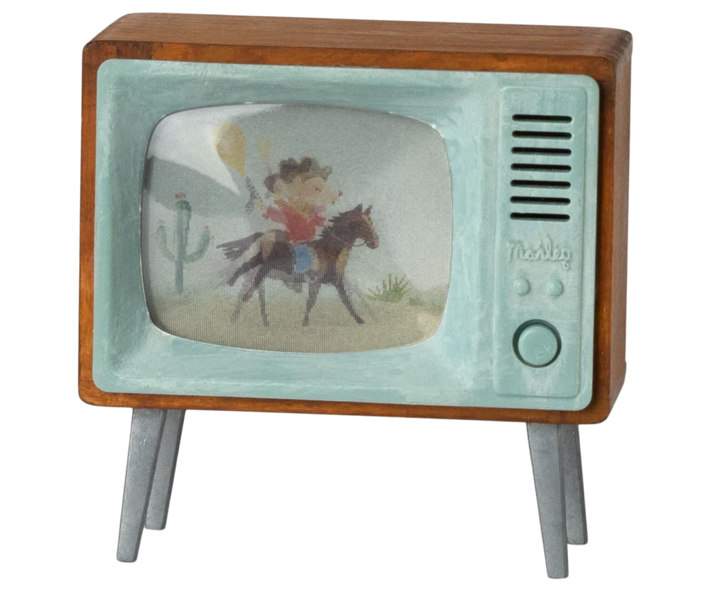 The Maileg Television, Mouse (expected 03/15/26) is a small vintage-style wooden TV with a blue front and gray legs, showing a cowboy in a desert—ideal as miniature decor or for your mousehouse television collection.