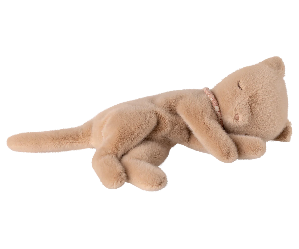 The Maileg Sleeping Kitten Plush, Small - Cream Peach, made from polyester, rests on its side with closed eyes and a pink beaded collar, creating an adorable scene reminiscent of a kitten peacefully napping.