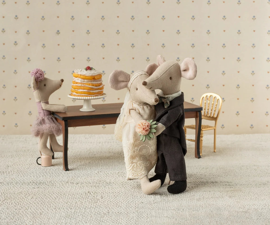Celebrate love with the Maileg Wedding Mice Couple in Box, Mum and Dad. This delightful set features two charming mice dressed as bride and groom, ready to dance at their wedding celebration. In a cozy, dollhouse-style room complete with a table and tall layered cake, this set is perfect as a wedding-themed gift or for collectors of adorable Maileg stuffed animals.