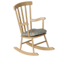 A beige PRE-ORDER: Rocking Chair, Mouse - Wheat with vertical slats and armrests features a cushioned seat. From Mouse hole Farmhouse, it is shown isolated on a white background. Estimated arrival mid August.