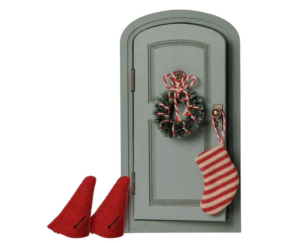 The PRE-ORDER: Maileg Christmas Door Set, Mouse (Estimated Arrival Early November) features a small arched gray door with a wreath, candy canes, striped stocking, and two red felt gnome hats—perfect for your festive Christmas decor.