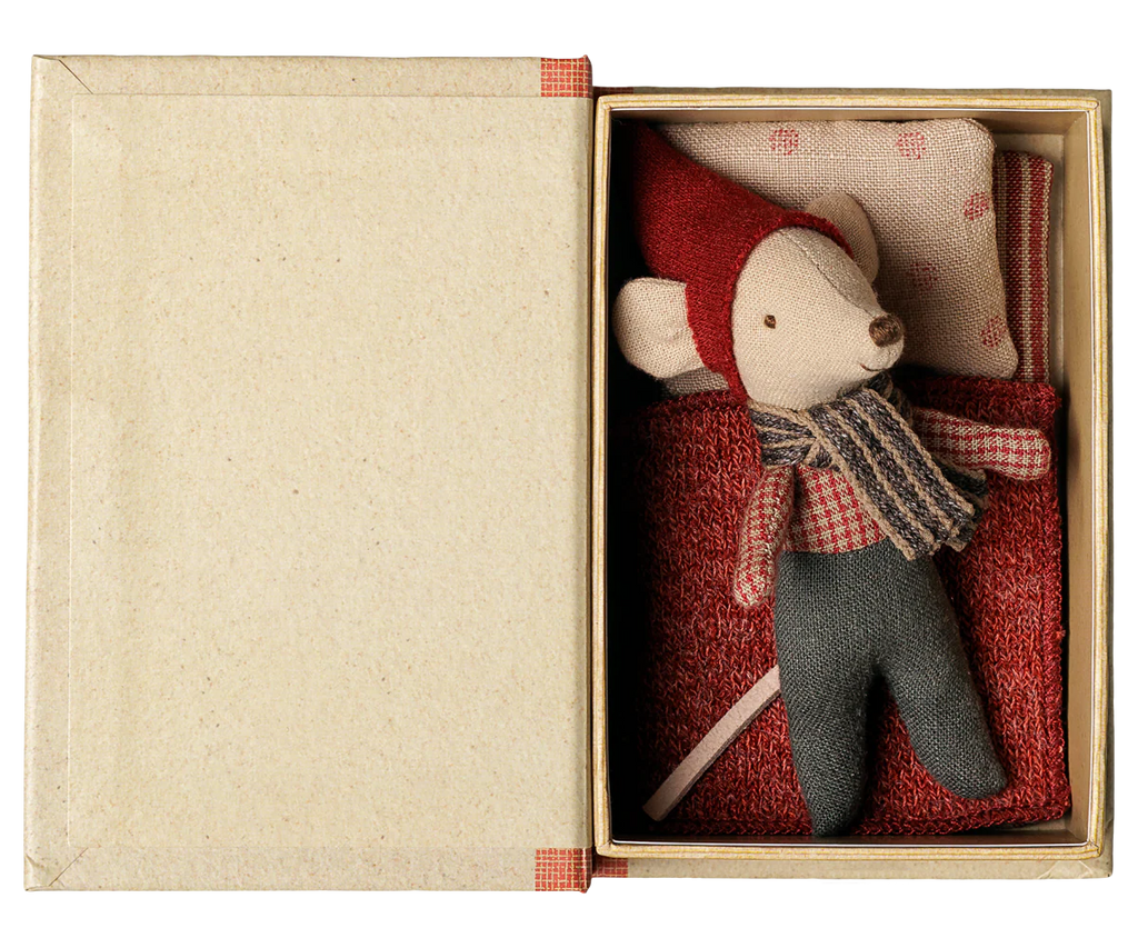 The PRE-ORDER: Maileg Christmas Mouse, Baby in Book (Estimated Arrival Early September) features a baby mouse in red hat, scarf, and pants, lying under a red blanket with a polka-dotted pillow inside an open book-shaped box.