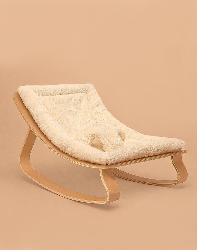 The Charlie Crane LEVO Baby Rocker features a sleek curved wooden frame and a soft 'Fur' cushion, shown against a plain beige background.