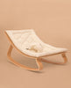 The Charlie Crane LEVO Baby Rocker features a light wooden frame and a soft, quilted organic white cushion, shown against a neutral beige background.