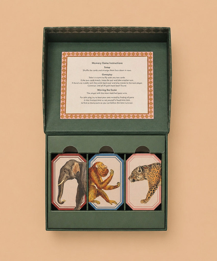 The Memory Game - Animal Kingdom is a boxed set featuring three stacks of vintage animal illustrations—elephant, monkey, and leopard—in an open green box with instructions inside the lid for this fun matching game.