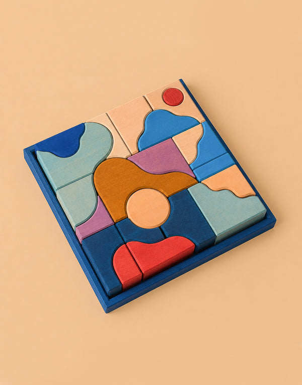 Grimm's Small Building Block Set - Wave features abstract, irregularly shaped wooden pieces in blue, red, pink, orange, and tan—perfect for creative building—arranged within a square blue frame on a beige background.