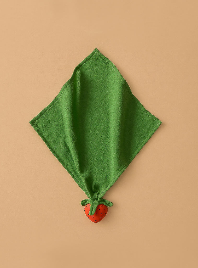 Sweetie the Strawberry Big Doudou, made of green organic cotton, is displayed diagonally on a beige background with a small red strawberry accent attached to one corner.