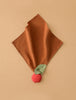 Pepa the Apple Big Doudou is a brown textured comfort toy made from organic cotton, featuring a green leaf and a red apple plush on one corner, shown on a beige background.