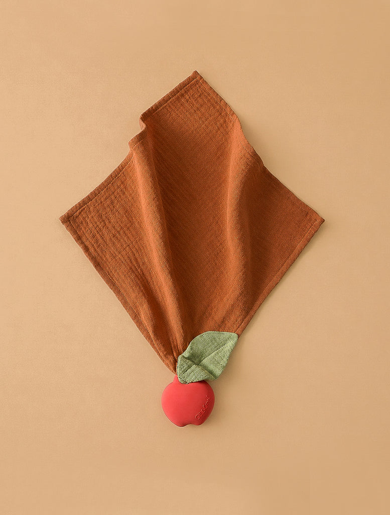 Pepa the Apple Big Doudou is a brown textured comfort toy made from organic cotton, featuring a green leaf and a red apple plush on one corner, shown on a beige background.
