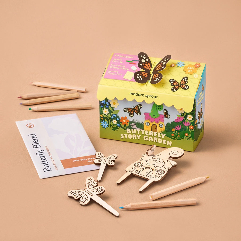 The Magical Minds Garden Kit is a colorful, plastic-free set for kids with a decorated box, wooden butterfly and flower markers, seed packet, instructions, and colored pencils—perfect for a fun STEM DIY activity on a beige surface.