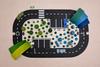 The WaytoPlay: Medium Flexible Toy Road Set - Expressway features black roads with white markings, parking spaces, and a play area of green and blue wooden blocks. A small green exit sign sits at the top left for imaginative play.