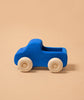 Grimm's Small Blue Truck, a non-toxic wooden toy with natural wood wheels and a blue body, sits on a plain beige background.