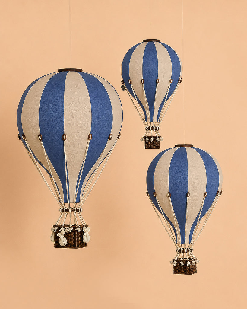 Three "Hot Air Balloon - Marine Blue" models are suspended against a beige background. Each wooden ornament features detailed baskets and ropes, creating the illusion of floating in midair—a charming handmade hot air balloon decoration perfect for children's room decor.