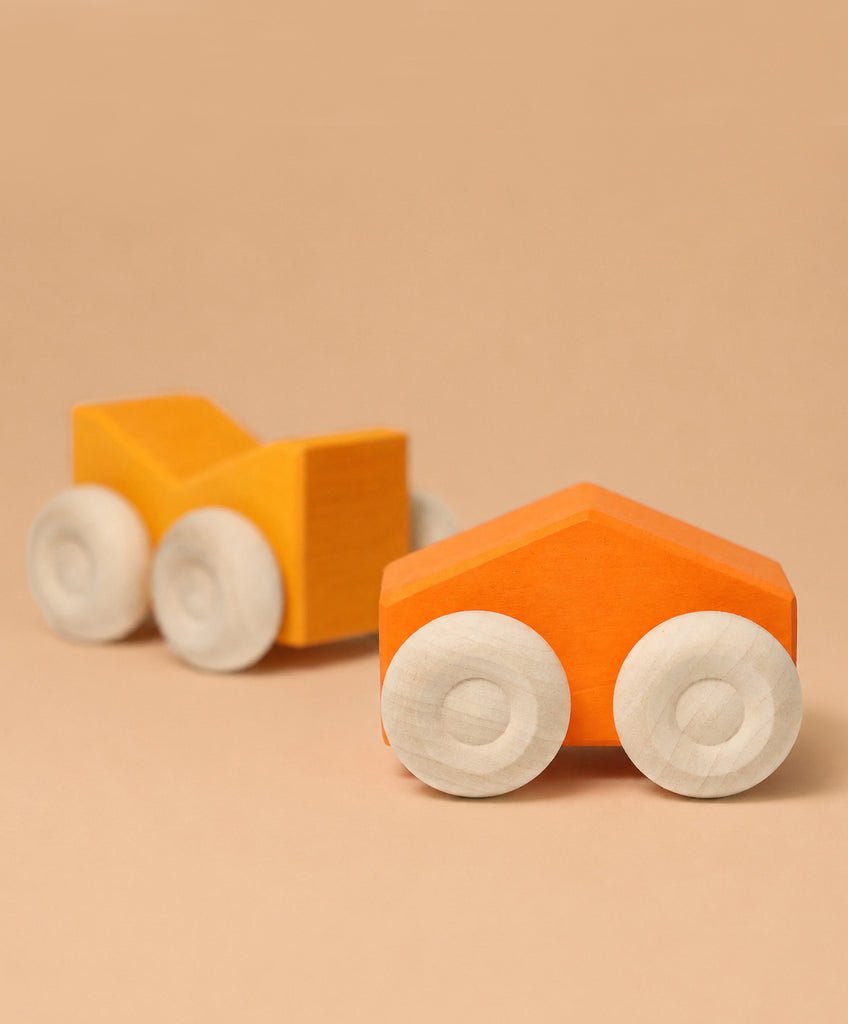 Two Grimm's Stacking Cars - Orange, wooden toy cars with white wheels in bright orange and yellow-orange, are displayed on a beige surface with a matching beige background.