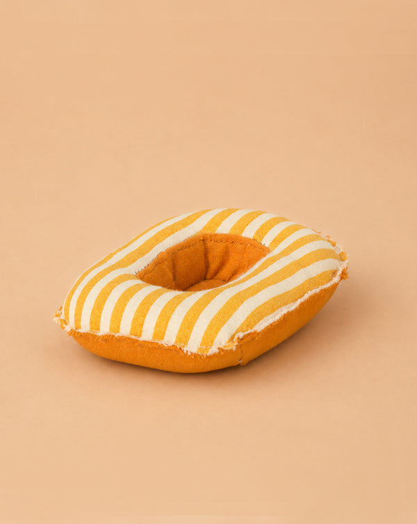 A soft, round yellow and white striped Maileg Rubber Boat for Small Mouse, featuring a central hole reminiscent of a donut, rests on a light tan background—perfect as a charming accessory for Maileg mice or as an adorable pretend boat for imaginative playtime adventures.