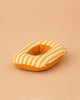 A soft, round yellow and white striped Maileg Rubber Boat for Small Mouse, featuring a central hole reminiscent of a donut, rests on a light tan background—perfect as a charming accessory for Maileg mice or as an adorable pretend boat for imaginative playtime adventures.