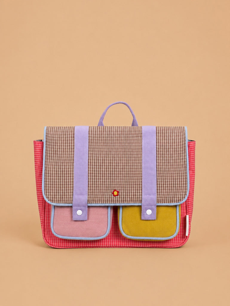 A Sticky Lemon School Bag from the Lemon Tree collection (Gingham Flower + Rose) is displayed against a plain beige background, featuring a colorful design with a checkered flap, purple straps, and front pockets in pink and yellow, all crafted from waterproof nylon.