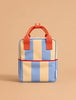 The Sticky Lemon Backpack Small | Stripes | Cloud Blue + Twiggy Beige features wide vertical blue and beige stripes, red handles, and a red accent trim. Made from recycled PET, this waterproof backpack stands upright against a light brown background.