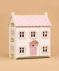 Sophie's Wooden Dolls House features a pink roof, white walls, and pink window shutters. Made from FSC-certified wood, it has a pink door with a heart-shaped window, green flower boxes, and sits against a solid beige background.
