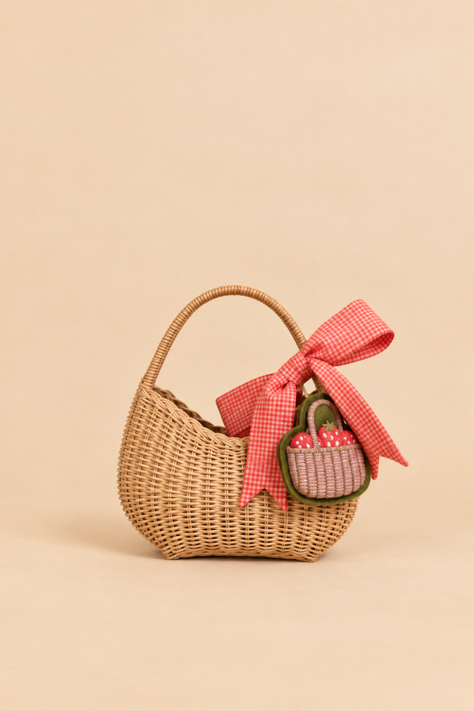 A delightful Sticky Lemon Wicker Basket | Lemon Tree, featuring a large red gingham bow and a small matching basket attached to the handle, set against a plain beige background—an ideal playful accessory for kids in the whimsical style of Sticky Lemon.