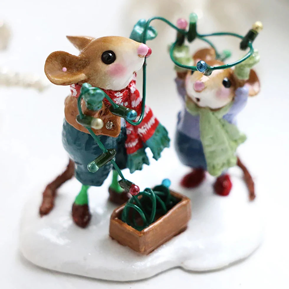 The Wee Forest Folk Tiny Collectible - Merry & Bright features two cheerful handmade mouse figurines in winter clothes, standing on snow and untangling green holiday lights from a box.