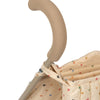 Close-up of a Konges Sloejd Doll Stroller - Multi Star handle covered in beige foam padding. The cream-colored fabric underneath is decorated with small, colorful stars in red, orange, blue, and green. The metal frame of the stroller is partially visible, along with its sturdy double wheels for added stability.