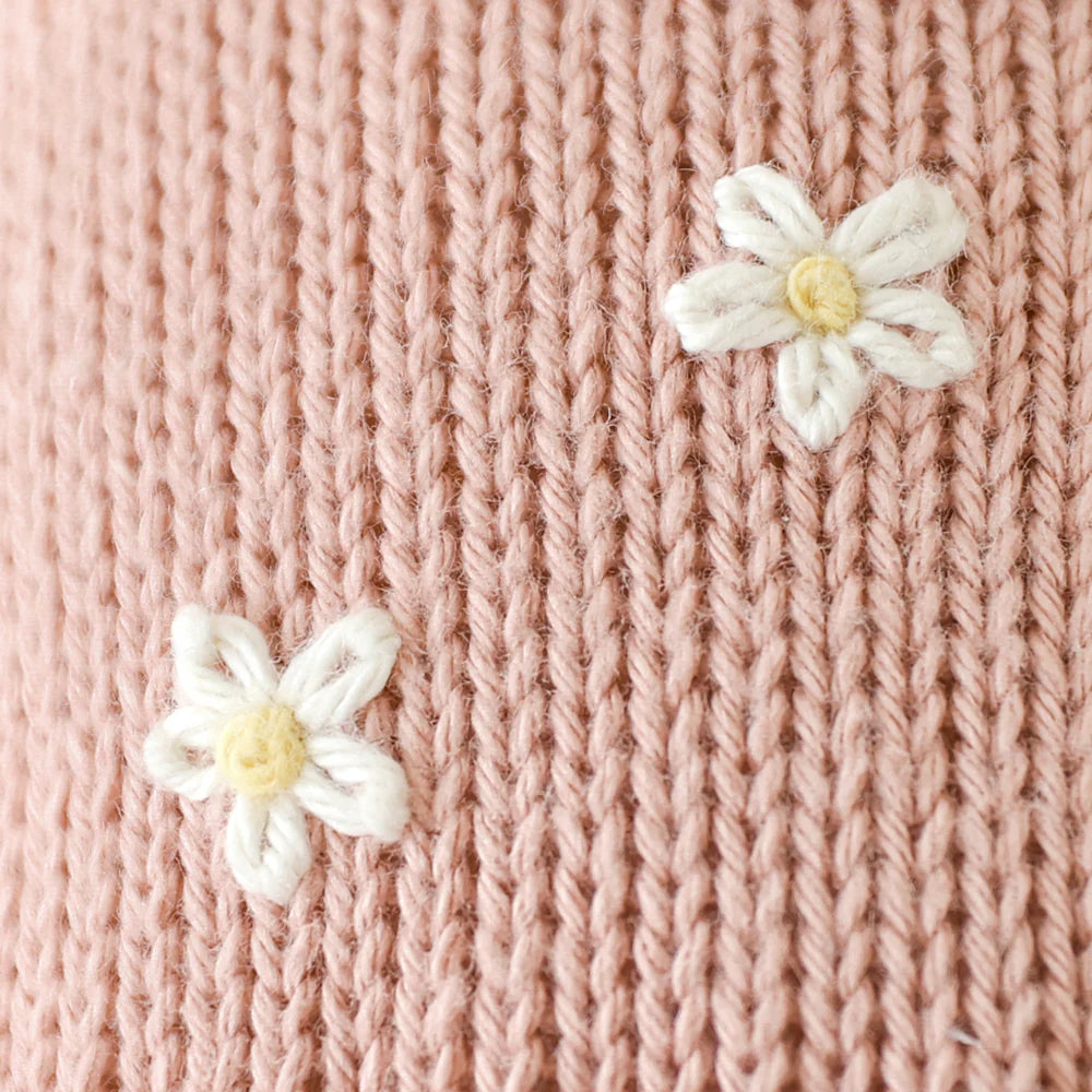 Close-up of Cuddle + Kind Daisy the Kitten's pink premium cotton knit, featuring two small white and yellow embroidered flowers.