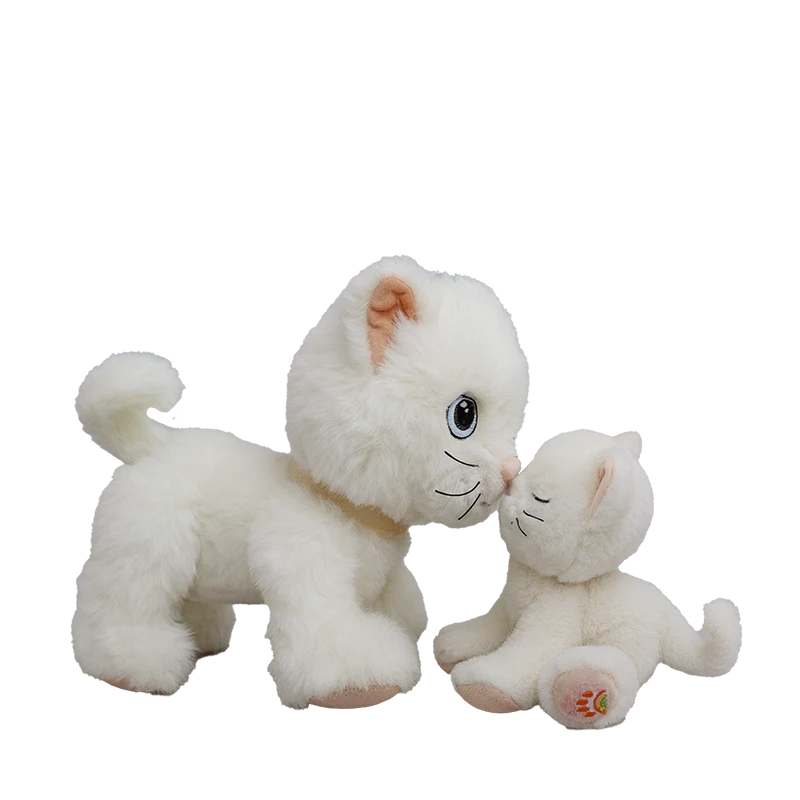 Two Olli Ella Dinkum Cat Lux plush kitties in white, one standing and one sitting, touch noses on a white background. This posable pair features big eyes and soft, fluffy fur for extra cuddly charm.