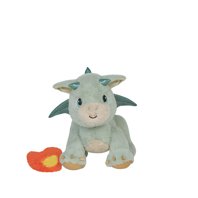 The Olli Ella Dinkum Dragon - Blaze - Green, a plush dragon toy with blue glittery horns and wings, sits beside a small orange heart-shaped accessory on a plain white background.
