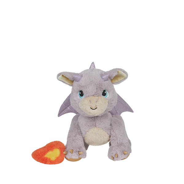 The Olli Ella Dinkum Dragon - Flare - Lavender, a plush purple dragon with blue eyes and a friendly smile, sits beside a red and yellow heart-shaped accessory, making the perfect magical companion on a white background.