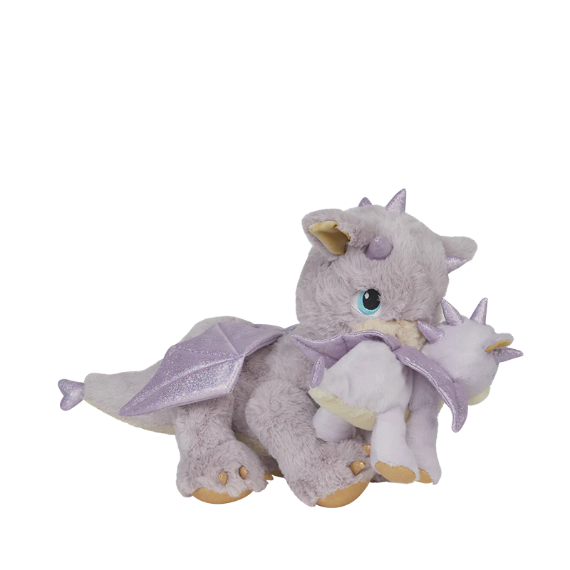 Meet the Olli Ella Dinkum Dragon - Flare in Lavender: a magical light purple plush dragon with shiny wings and horns, holding a matching baby dragon in its mouth. Both have blue eyes and are pictured on a plain white background.
