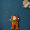 An Olli Ella Dinky Dinkum Doll - Jules Jack-O’-Lantern dressed in a plush orange pumpkin suit, posed against a dark blue background featuring a moon, clouds, and stars.